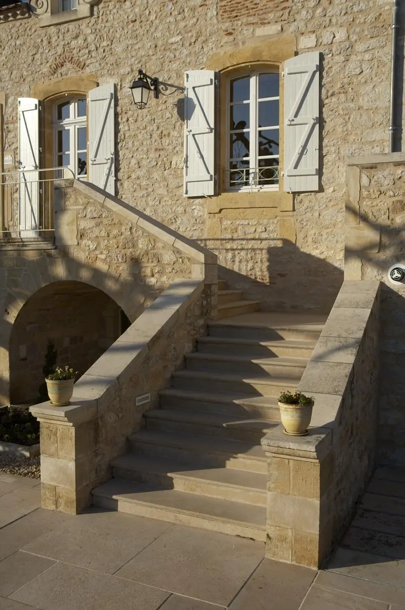 Habillage d’un escalier extérieur en pierre naturelle, sublimant l’entrée d’une maison avec élégance.