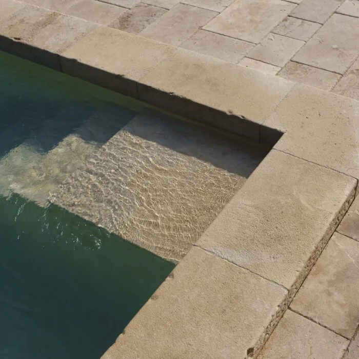 Marche de piscine en pierre naturelle d’Auberoche en massif, pour accès bassin extérieur.